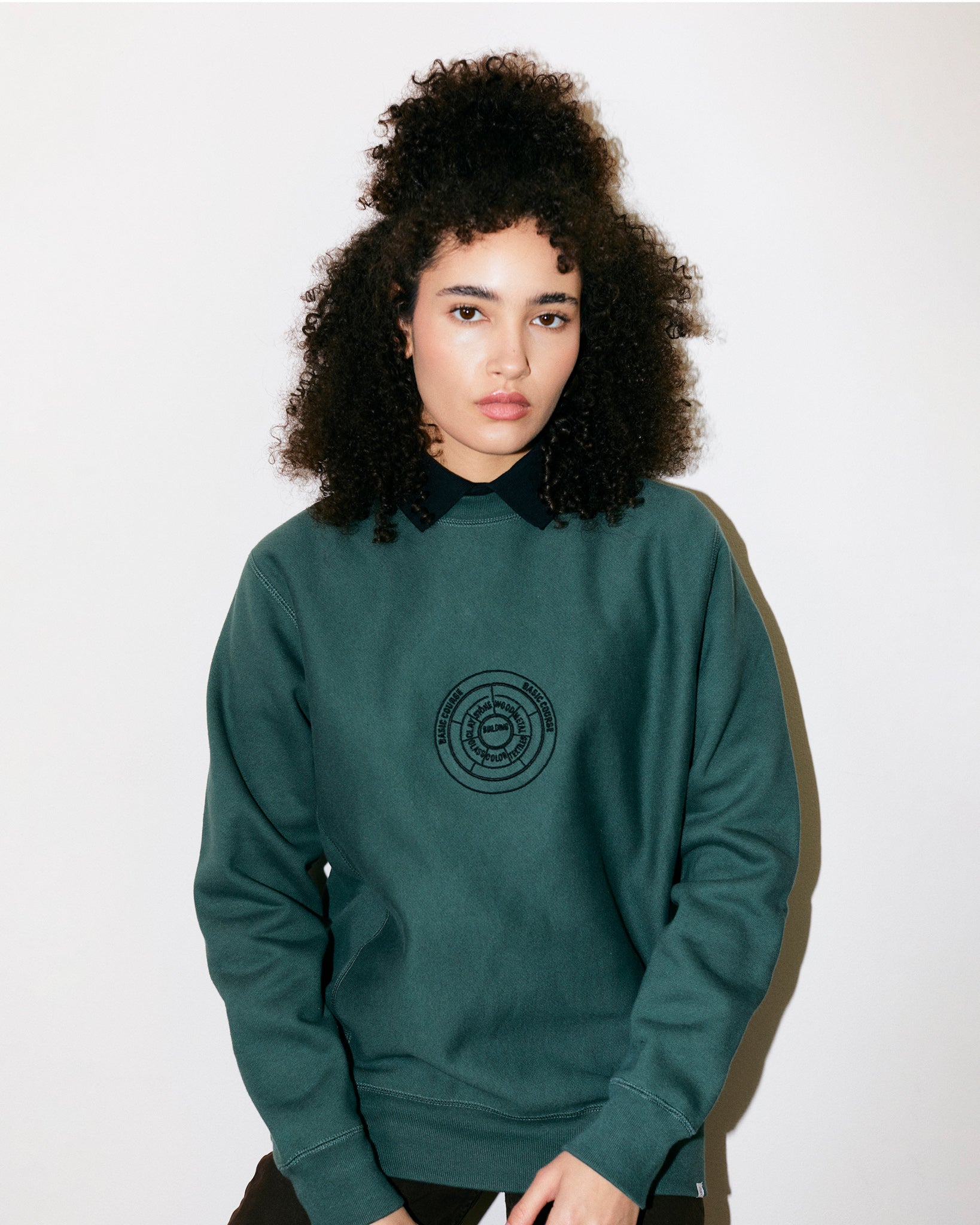 Teodora Marcella wears Green / Viridian Heavyweight Sweatshirt / Crewneck with embroidered print of the Bauhaus School Conceptual Curriculum Diagram and the Official Bauhaus seal on the back.